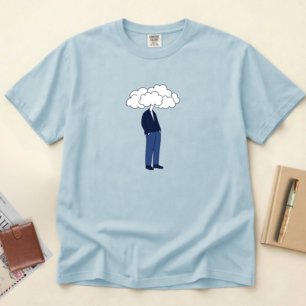 Light blue t-shirt with a graphic of a person under a cloud on a beige background