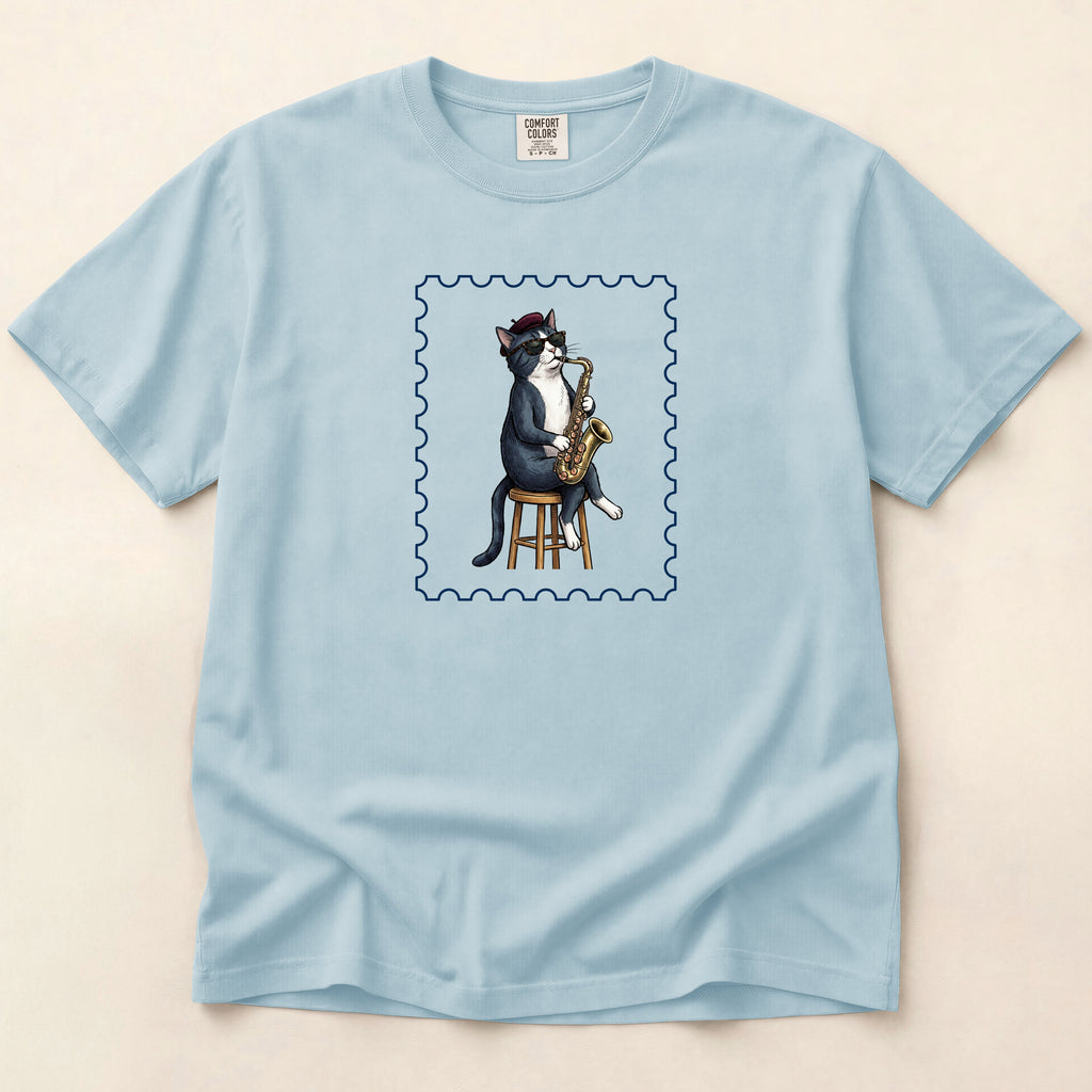 Light blue t-shirt with a cat playing saxophone design on a beige background