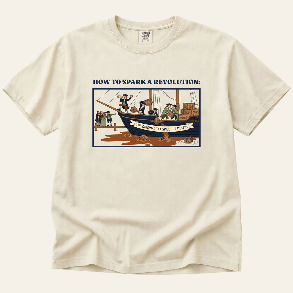 Beige t-shirt with graphic design of a ship and text on a white background