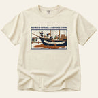 Beige t-shirt with graphic design of a ship and text on a white background