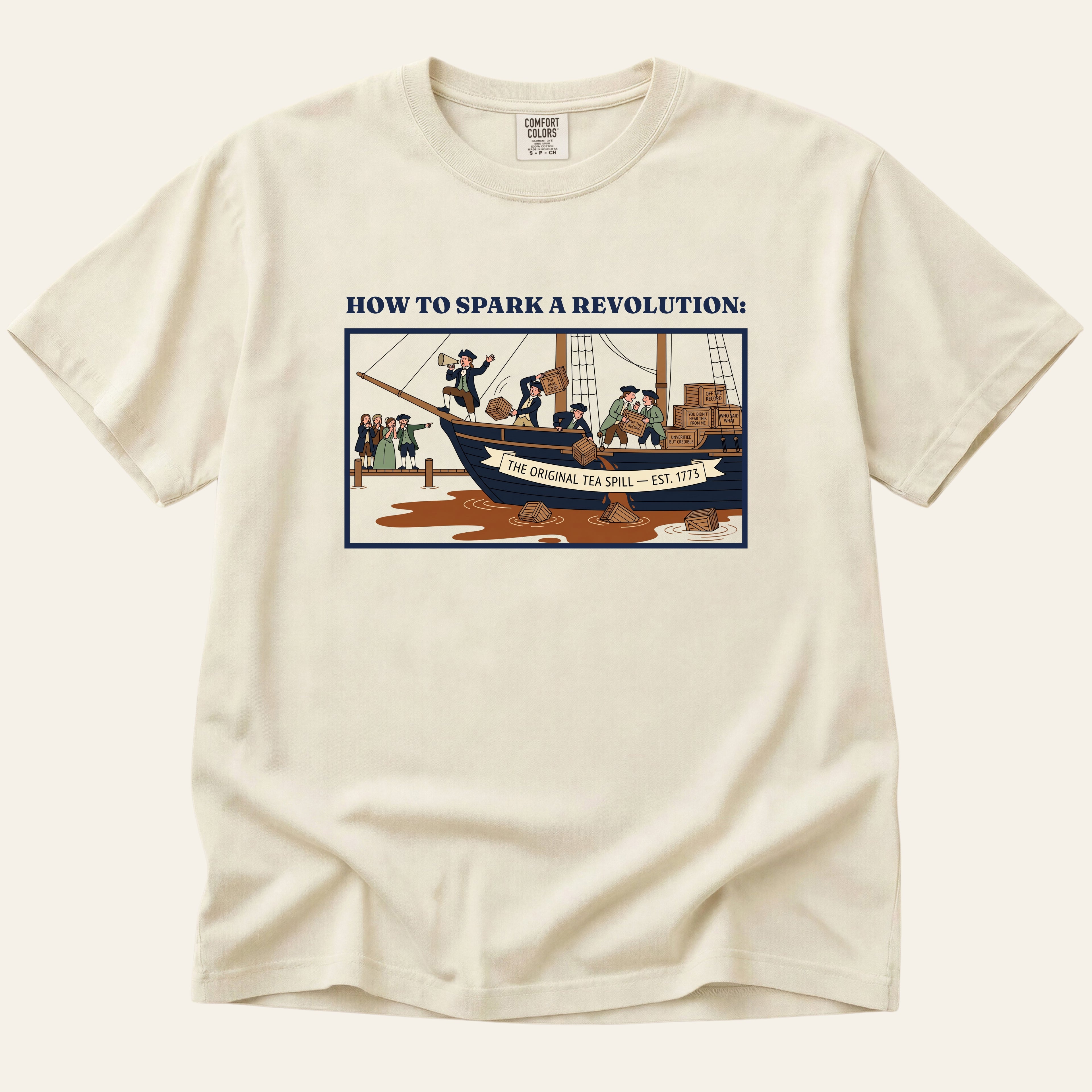 Beige t-shirt with graphic design of a ship and text on a white background